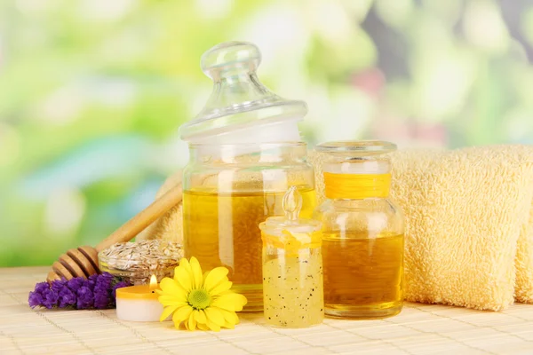 Fragrant honey spa with oils and honey on wooden table on natural background