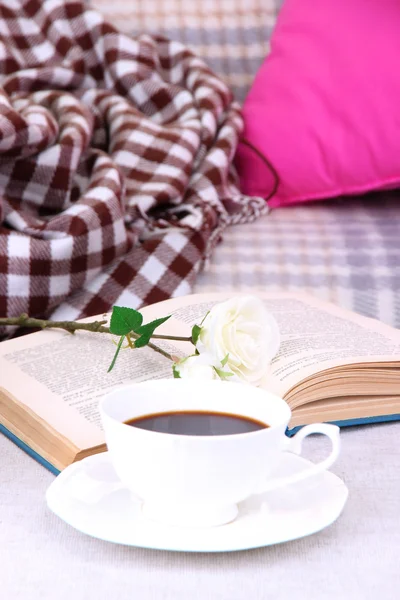 Composition with cup of drink, book and flowers on home interior background
