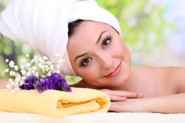 Beautiful young woman with towel on her head on bright background