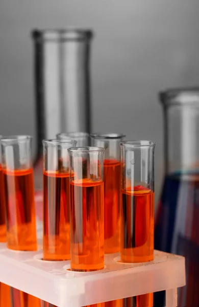 Laboratory pipette with drop of color liquid over glass test tubes, close up