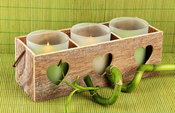 Wooden candlestick with candles and bamboo, on green mat