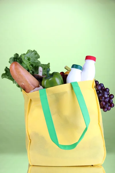 Eco bag with shopping on green background
