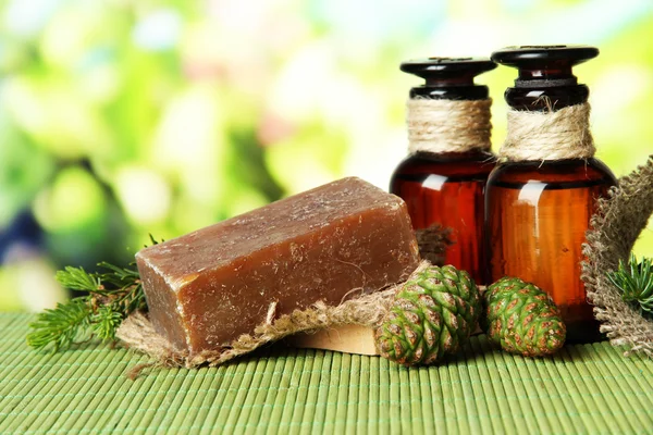 Hand-made soap and bottles of fir tree oil on bamboo mat