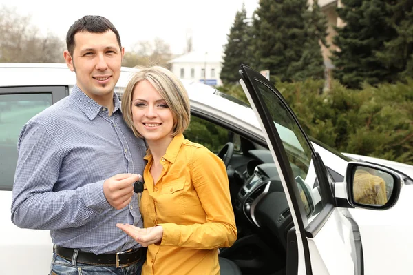 Portrait of happy beautiful couple with car keys, standing near the car