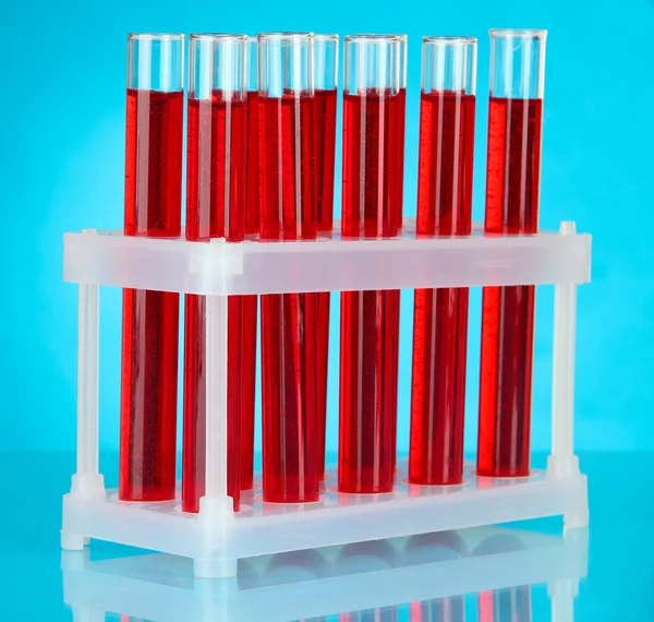 Test tubes with blood in laboratory on blue background