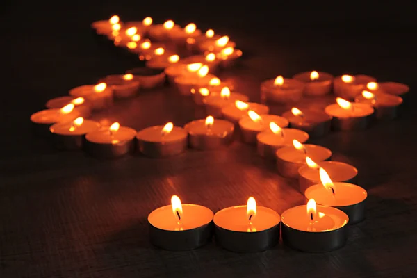 Burning candles as treble clef on dark background