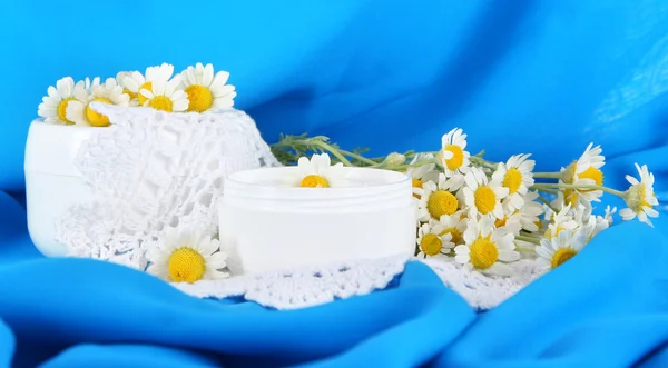 Cream with chamomile on napkin on blue fabric background
