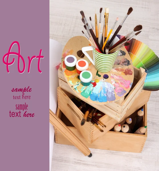 Wooden easel with clean paper and art supplies in room