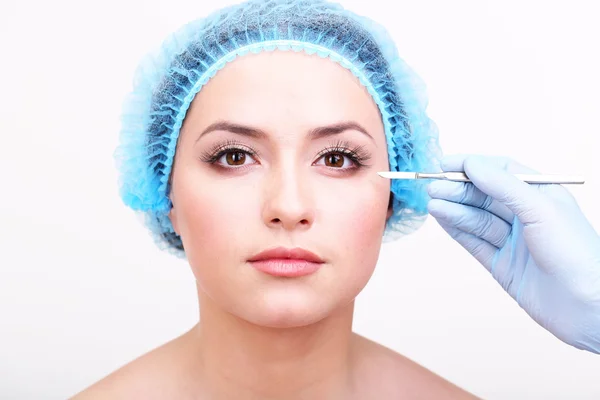 Cosmetic surgery with scalpel on young woman close up