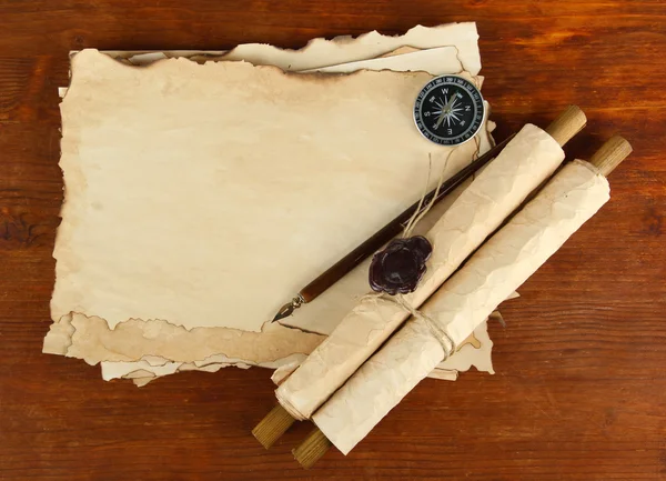 Old paper, scrolls and compass on wooden background