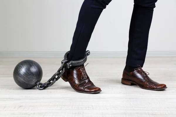 Business worker with ball and chain attached to foot