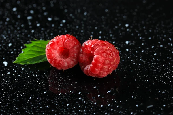 Ripe sweet raspberries with drops on dark background
