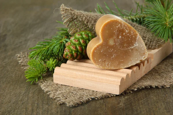 Hand-made soap and green pine cones on wooden background