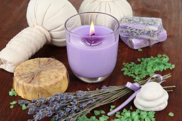 Still life with lavender candle, soap, massage balls, bottles, soap and fresh lavender, on wooden table on wooden background