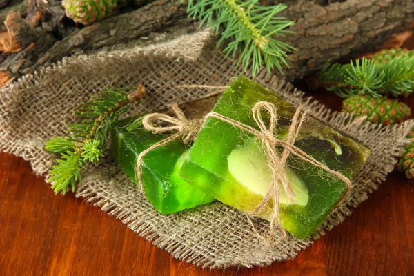 Hand-made soap and green pine cones on wooden table