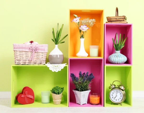 Shelves of different bright colors with decorative addition on wall background