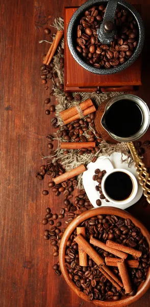 Coffee beans, metal turk and coffee mill on wooden background with copy space