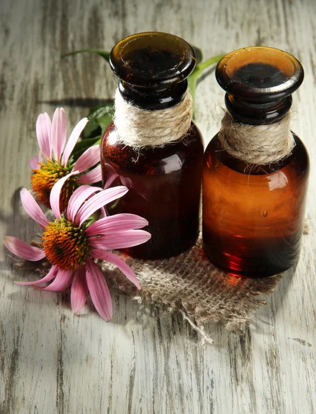 Medicine bottles with purple echinacea flowers on wooden table