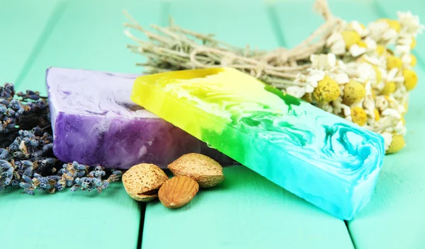 Pieces of handmade soap with herbs, on color wooden background