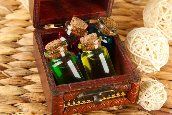 Bottles with colored liquids in box on wicker wooden background