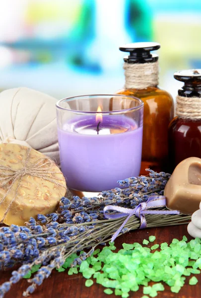 Still life with lavender candle, soap, massage balls, bottles, soap and fresh lavender, on wooden table on bright background