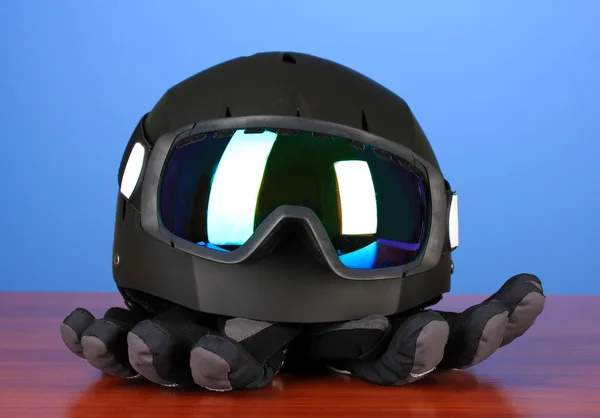 Winter sport glasses, helmet and gloves, on blue background