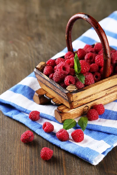 Ripe sweet raspberries in basket on wooden background