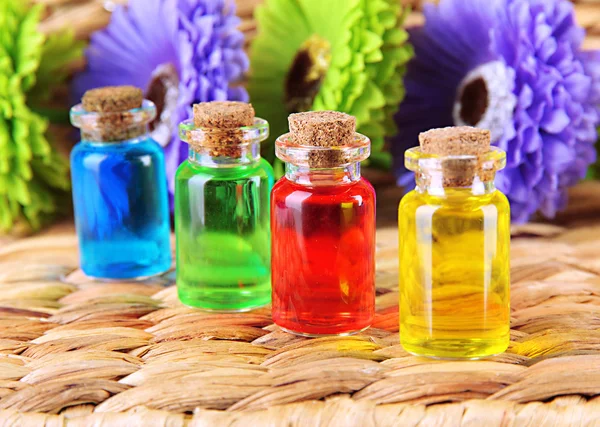 Bottles with colored liquids on wicker wooden background