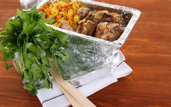 Food in boxes of foil on wooden background