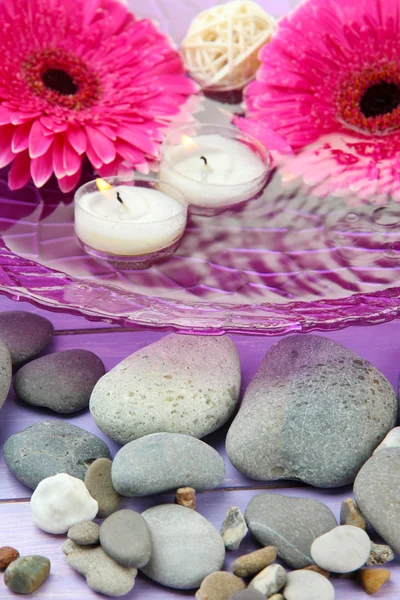 Beautiful gerbera flowers, stones and candles on water