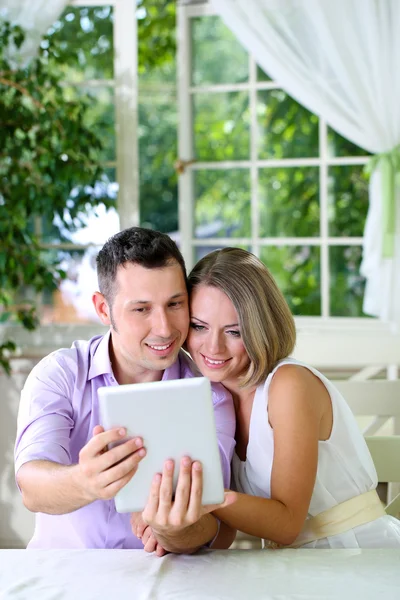 Young couple taking photo with tablet in restaurant