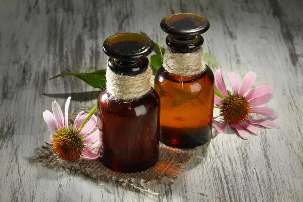 Medicine bottles with purple echinacea flowers on wooden table