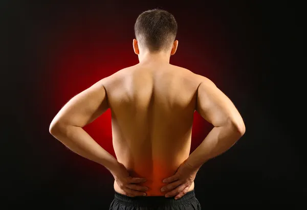 Lower back pain in man on dark background