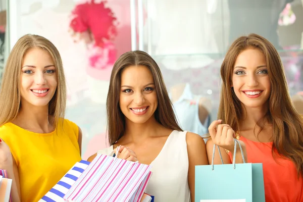 Three beautiful young woman in shop with shopping bags