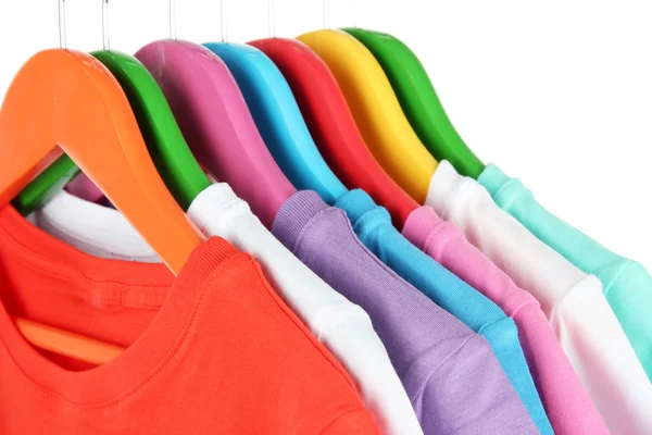 Different shirts on colorful hangers on white background