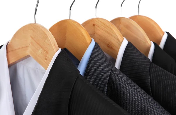 Suits with shirts on hangers on white background