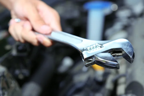 Hand with wrench. Auto mechanic in car repair