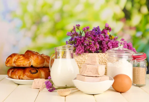 Dry yeast with pastry and baking ingredients on wooden table on natural background