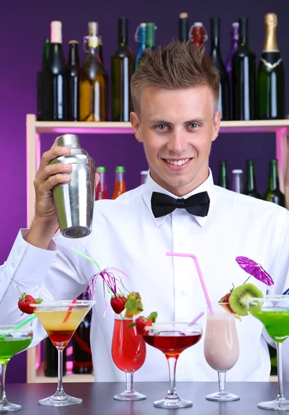 Portrait of handsome barman with different cocktails cocktail, at bar