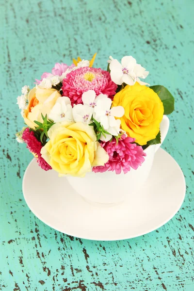 Beautiful bouquet of bright flowers in color vase, on bright background