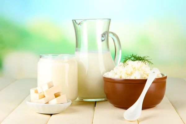 Fresh dairy products on wooden table on natural background