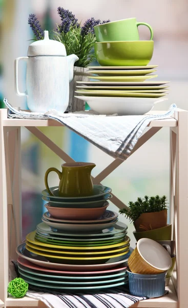 Beautiful white shelves with tableware and decor, on bright background, close-up