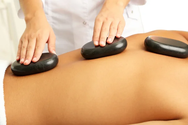 Young man having stone massage in spa salon