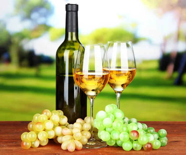 Ripe grapes, bottle and glasses of wine, on bright background