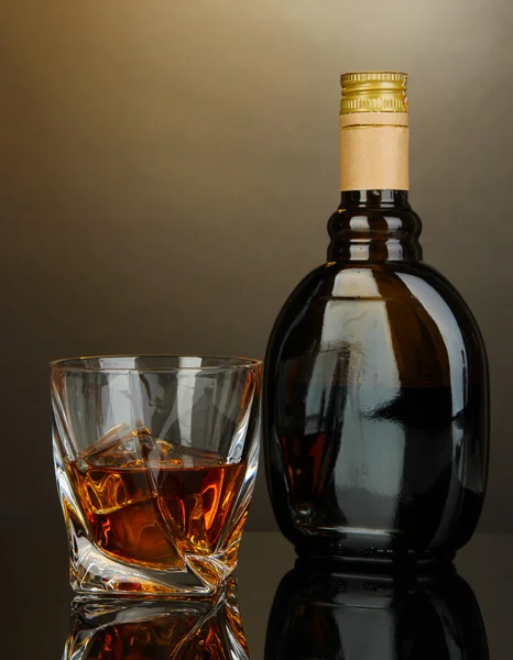 Glass of liquor with bottle, on dark background