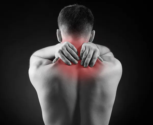 Young man with neck pain, on red background