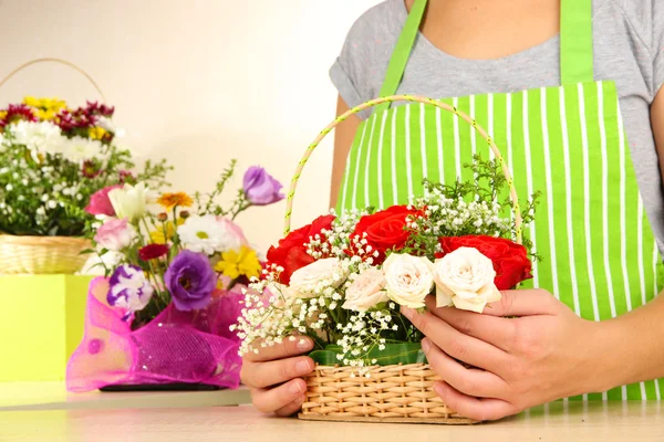 Florist makes flowers bouquet in wicker basket