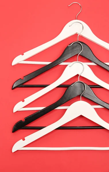 Black and white clothes hangers on color background