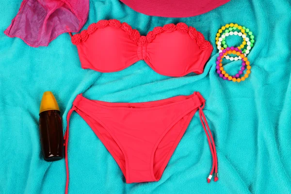 Swimsuit and beach items on bright blue background