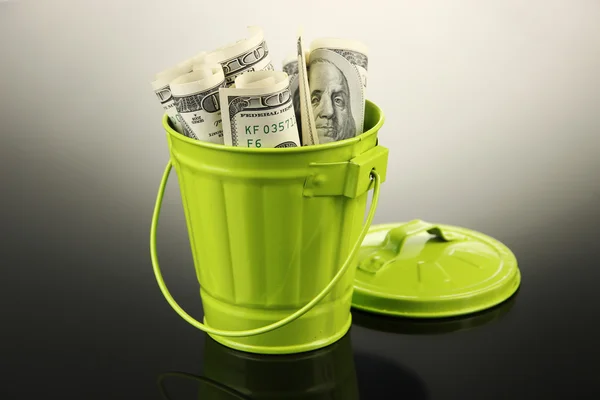 Money in trash can, on dark background